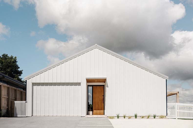 White Barndominium With Wooden Door